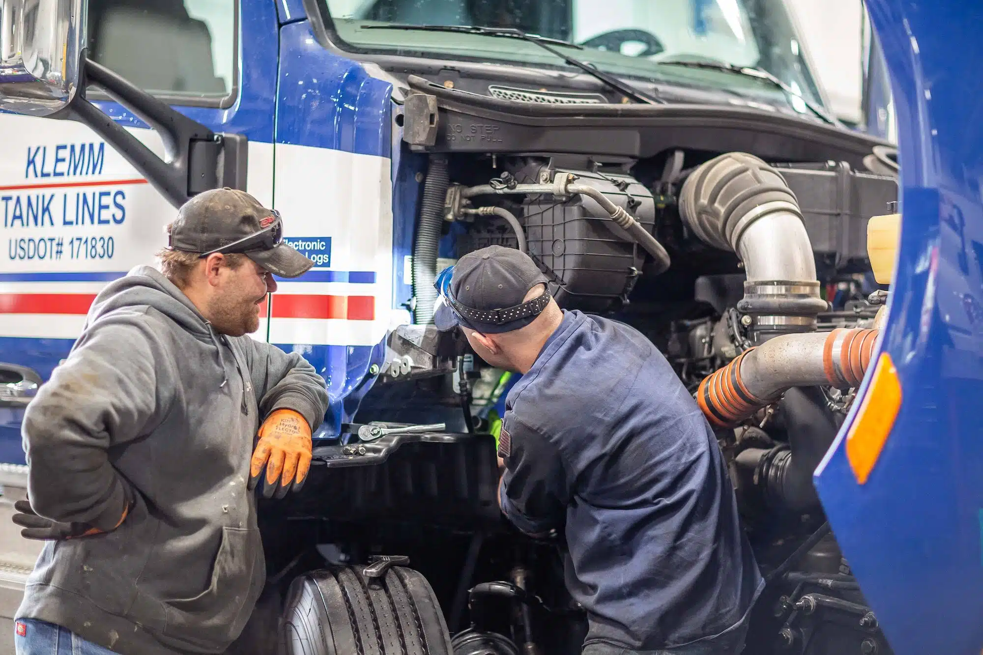 Two people working on truck engine
